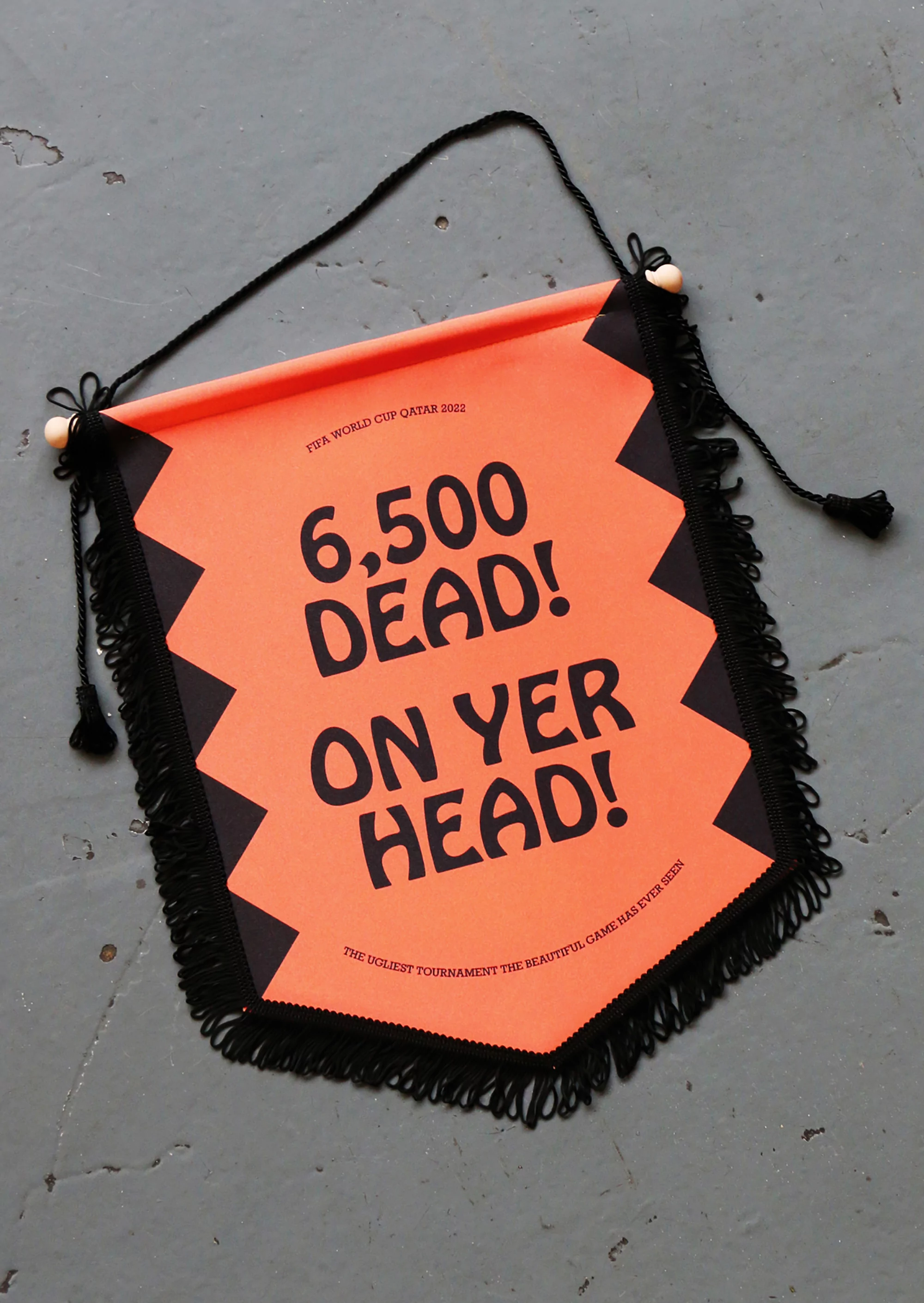 Orange banner with black fringe hanging against a grey floor; bold black text reads '6,500 DEAD! ON YER HEAD!'