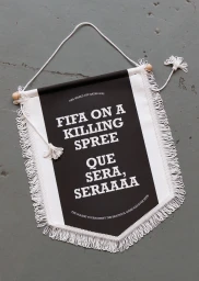 Black and white fabric pennant flag hanging against a grey surface displaying bold typography