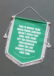 Green pennant hanging on a grey wall with white text reading about Frank Lampard's disallowed goal against Germany