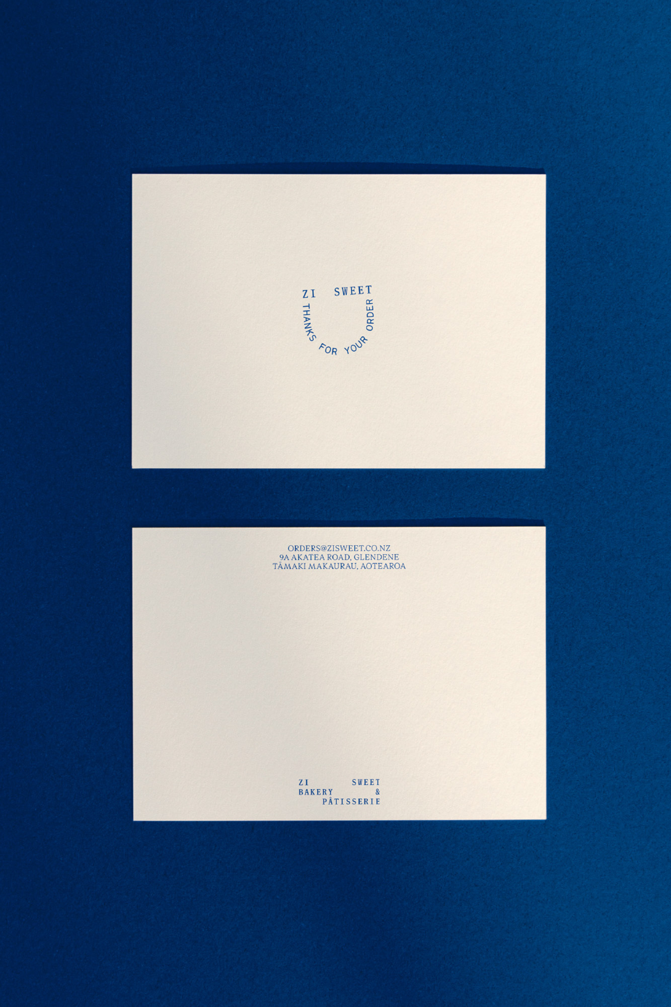 Two white cards with blue text sit on a dark blue surface, one displaying 'It Sweet' and the other showing contact information.