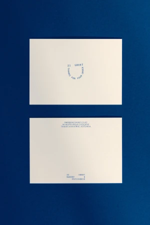 Two white cards with blue text sit on a dark blue surface, one displaying 'It Sweet' and the other showing contact information.