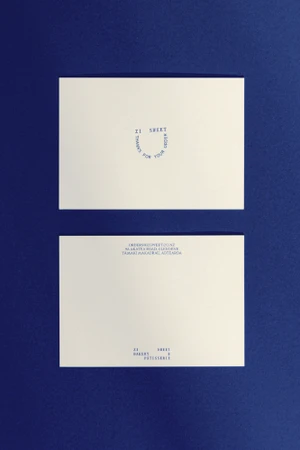 Two white stationery cards featuring blue typography resting on a dark blue textured surface.