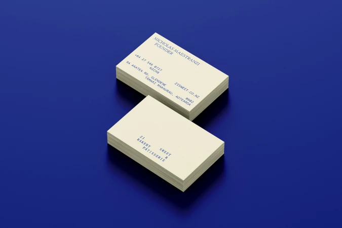 Two stacks of cream-colored business cards with blue typography resting on a glossy deep blue background