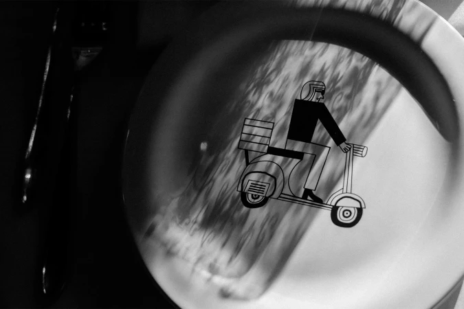 Monochrome art of a person riding a delivery scooter on a white plate, creating a modern and artistic scene with graphic illustration.