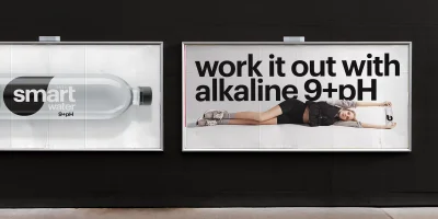 Two billboard advertisements for smartwater mounted on a dark exterior wall, showing product and model shots.