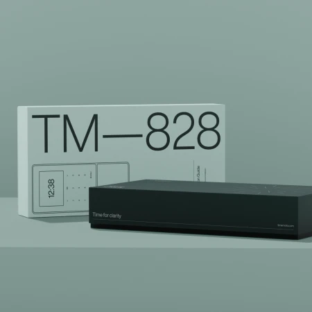Product shot featuring a black electronic device box with a white box behind it, both on a muted green surface.