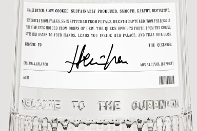 Close-up of a Casa Malka Blanco glass bottle featuring a white paper label with bold black typography and embossed lettering at the base.