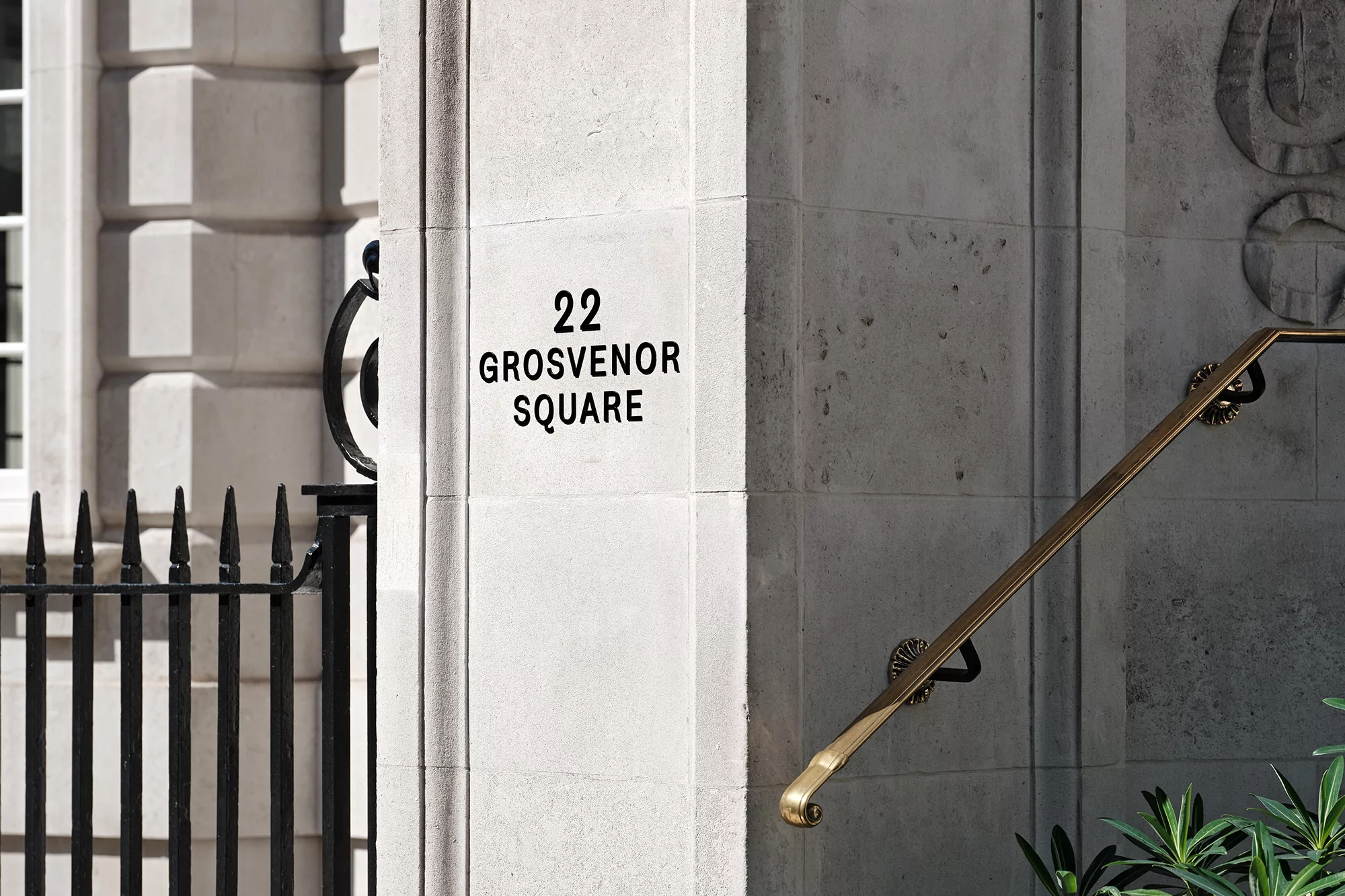 Exterior of 22 Grosvenor Square building with stone facade, black iron gate, and brass handrail; an elegant architectural detail.
