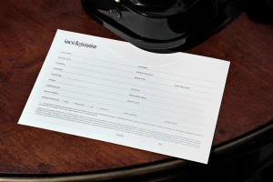 Guest registration form resting on a dark wood table with a black telephone object visible at the top.