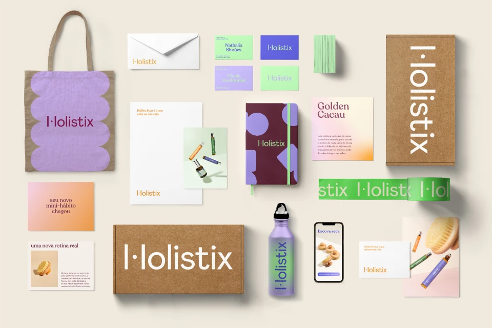 Promotional flat lay of Holistix-branded items: tote bag, stationery, water bottle, boxes, cards, and mobile phone on neutral backdrop.