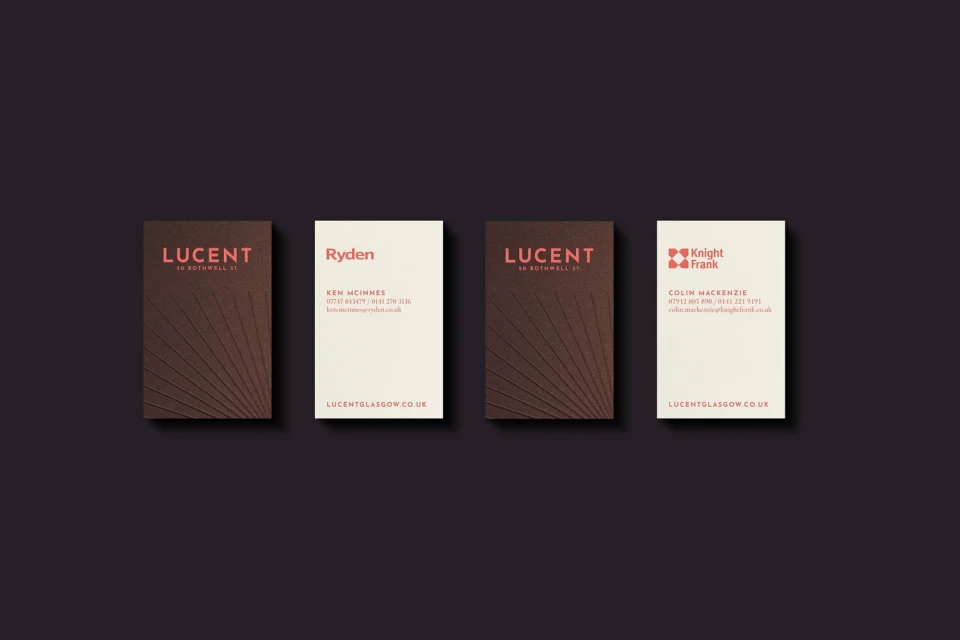 Close-up of four business cards with various company names and contact information, displayed on a dark background in a studio setting.
