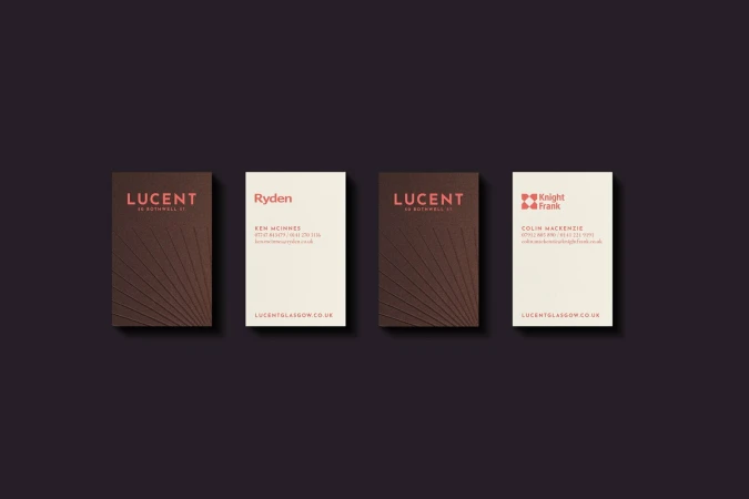 Close-up of four business cards with various company names and contact information, displayed on a dark background in a studio setting.