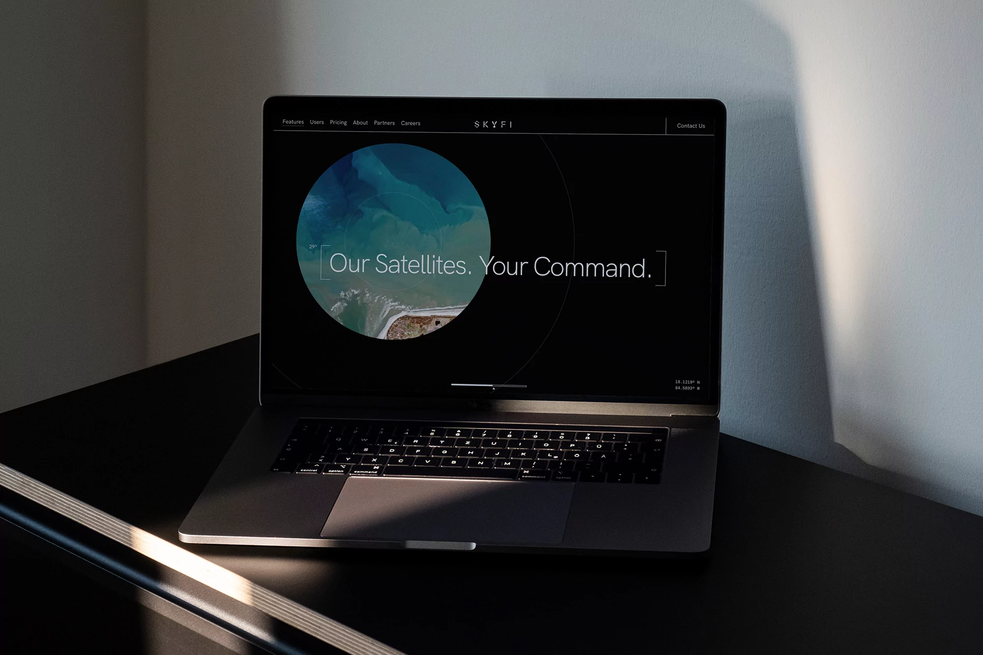 Laptop displaying the SKYFI website, featuring a satellite image and the tagline 'Our Satellites. Your Command.', in a modern indoor setting.
