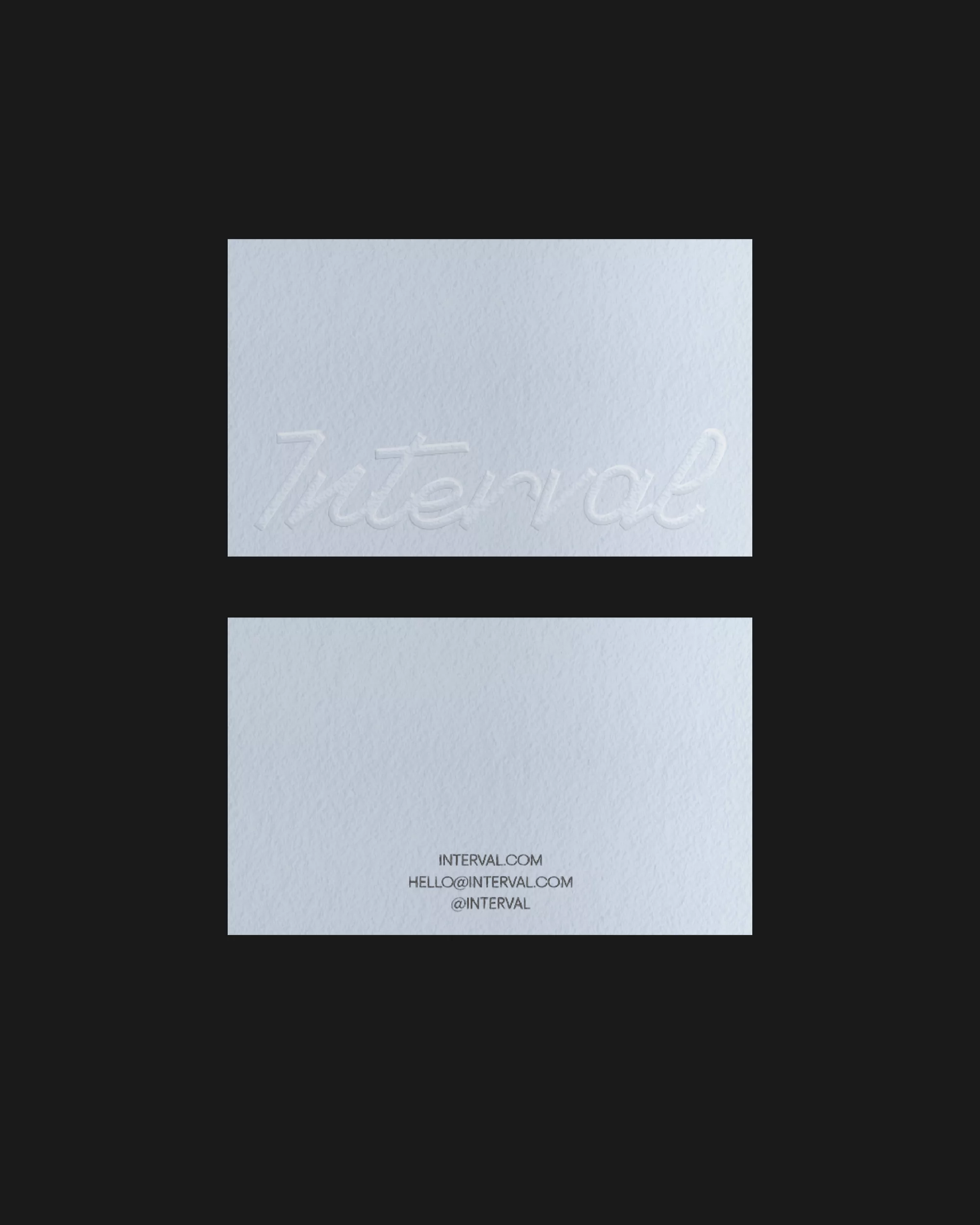 Two white business cards are displayed on a black surface, featuring the word 'Interval' embossed on the top card.