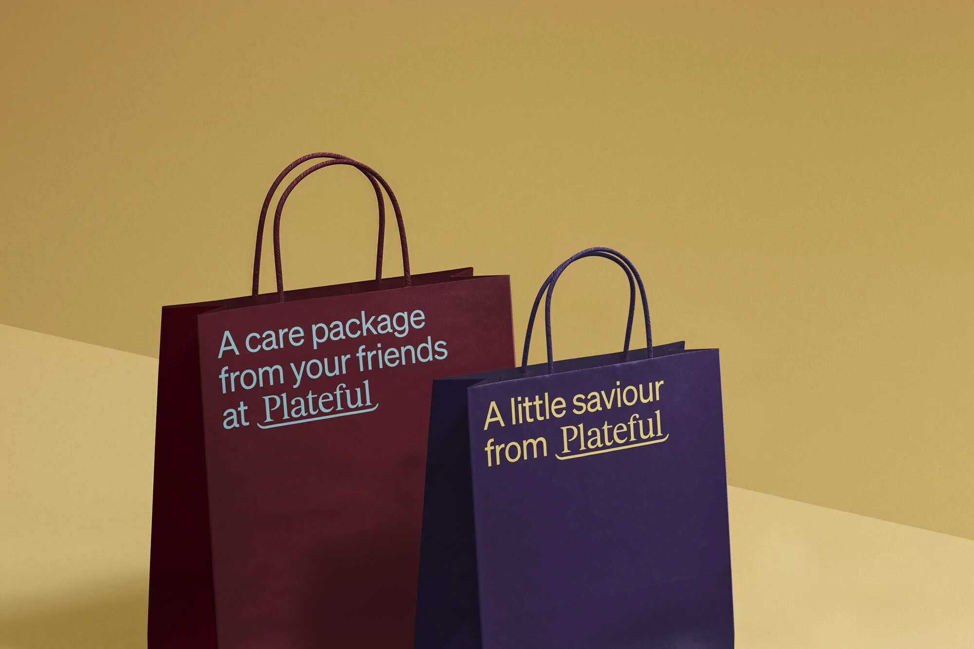 Two shopping bags against a solid yellow background, one red, one purple, both with the text 'Plateful' in gold.
