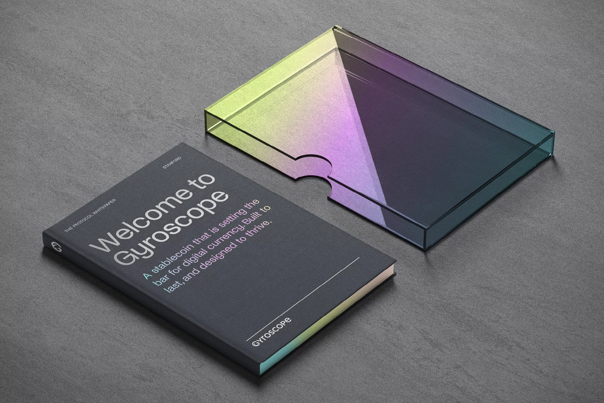 Book titled 'Welcome to Gyroscope' next to a transparent box with a rainbow gradient, shot in a studio setting on a grey surface.