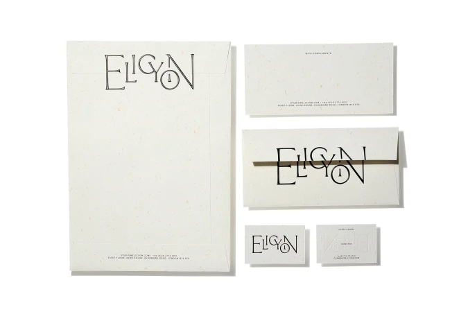 Flat lay photograph of branded stationery set including envelopes, letterhead, and business cards on white paper.