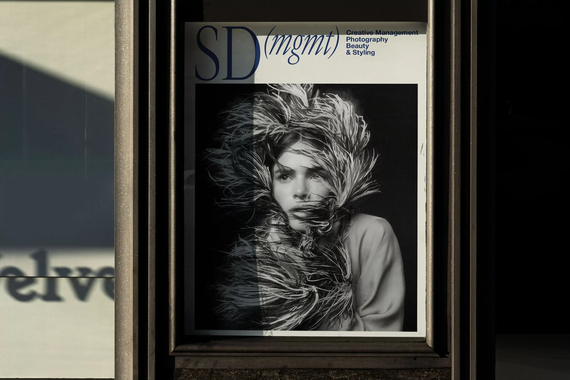 Black-and-white image of a magazine cover displayed in a window. The cover features a person with feathered adornments around their head.