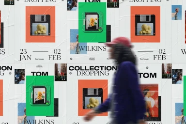Motion blurred person walking past a poster wall with typographic branding and colourful squares.