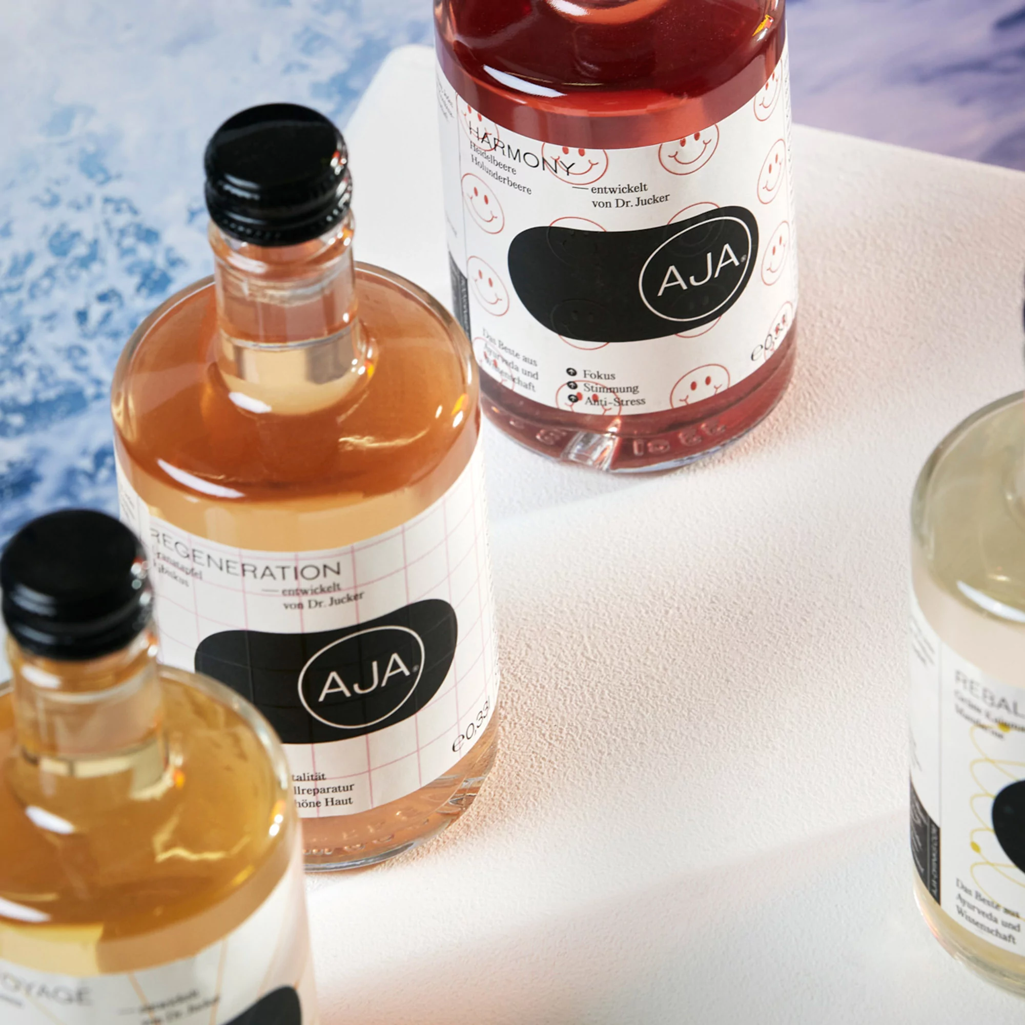 Various clear glass bottles filled with colorful liquids and labeled with black and white labels on a white surface.