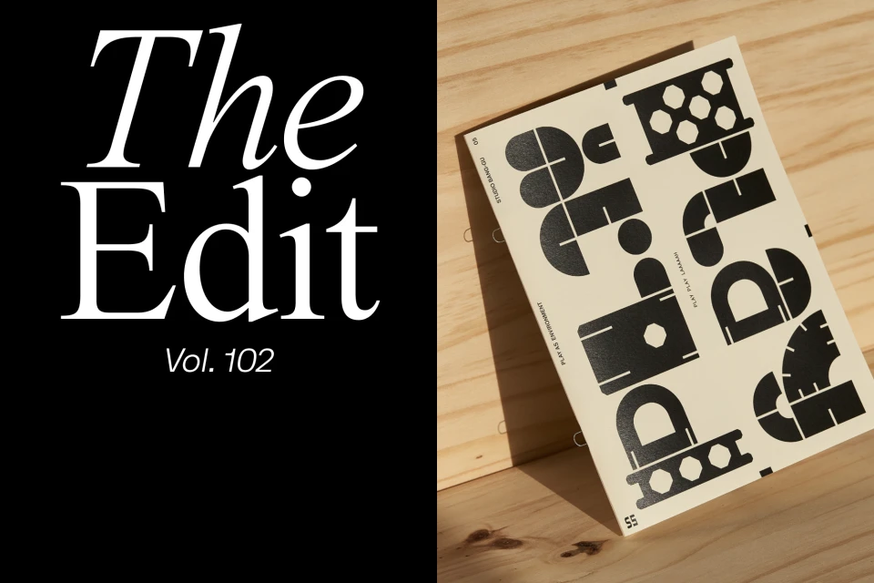 Art book lying on a wooden surface with abstract geometric shapes in black on a cream background, next to The Edit magazine cover.