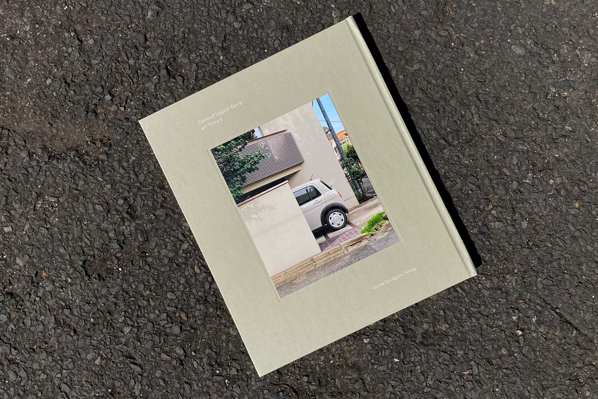 Book cover featuring a photograph of a white car parked near a building, on a textured black surface under natural lighting.