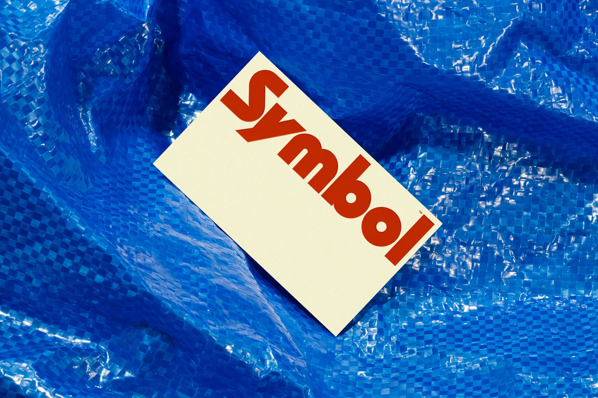 White card with the word 'Symbol' in red font, set against a textured blue material, creating a textured background.