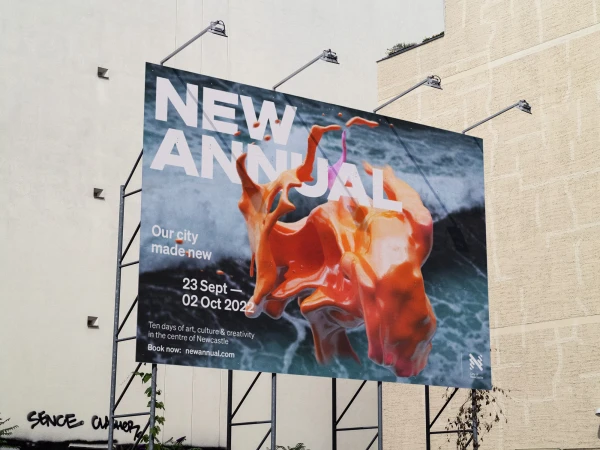 Billboard advertising a city art festival featuring abstract orange art, promoting art, culture, and creativity in Newcastle, UK, 2022.