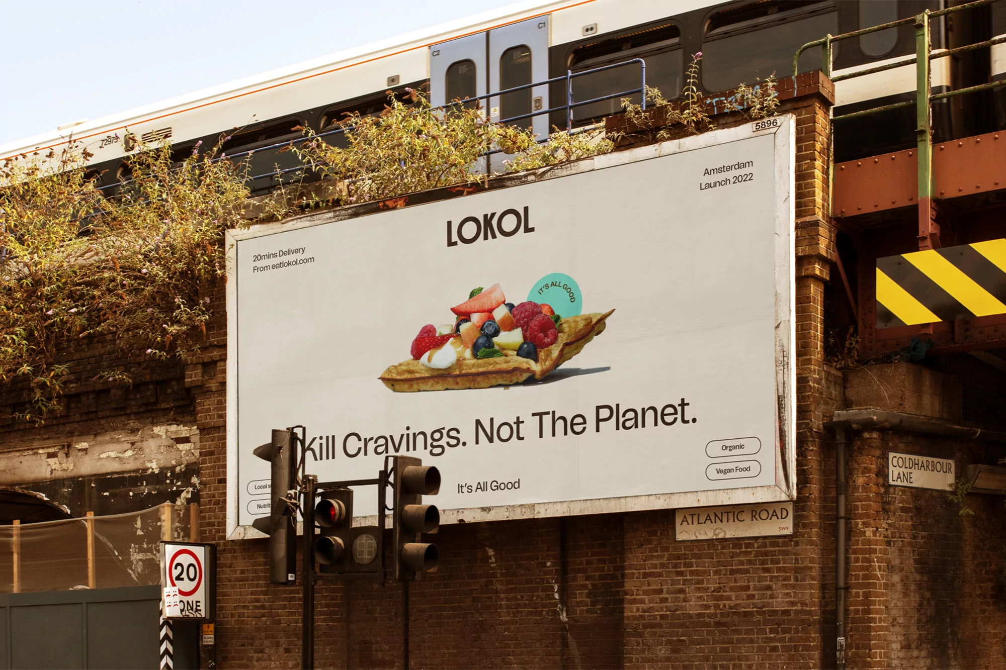 Outdoor billboard advertisement for Lokol brand featuring a waffle topped with fruit; image includes train tracks and traffic lights.