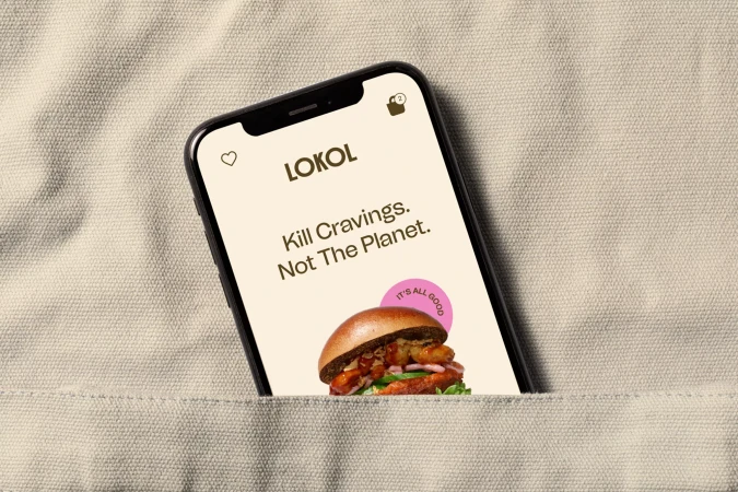 Smartphone displays food app showcasing a burger, set against a textured beige background. Food and Beverage application on mobile device.