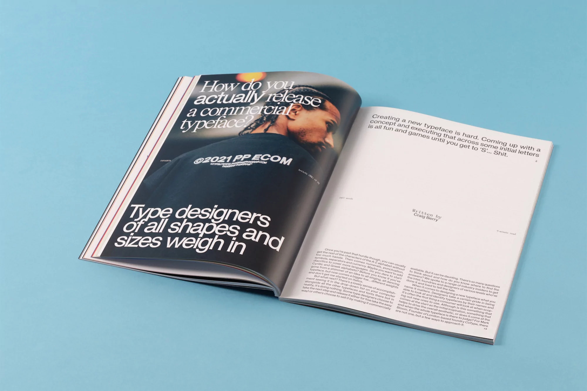 An open magazine spread featuring bold typographic headlines and a black t shirt against a blue background.