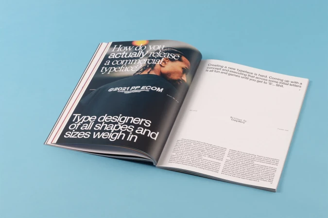 An open magazine spread featuring bold typographic headlines and a black t shirt against a blue background.