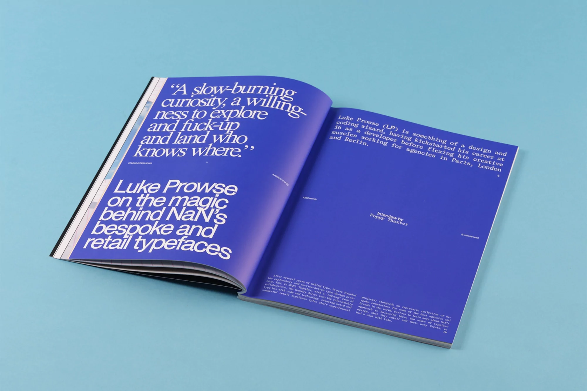 An open magazine spread featuring bold white typography on vibrant blue pages against a solid blue background.