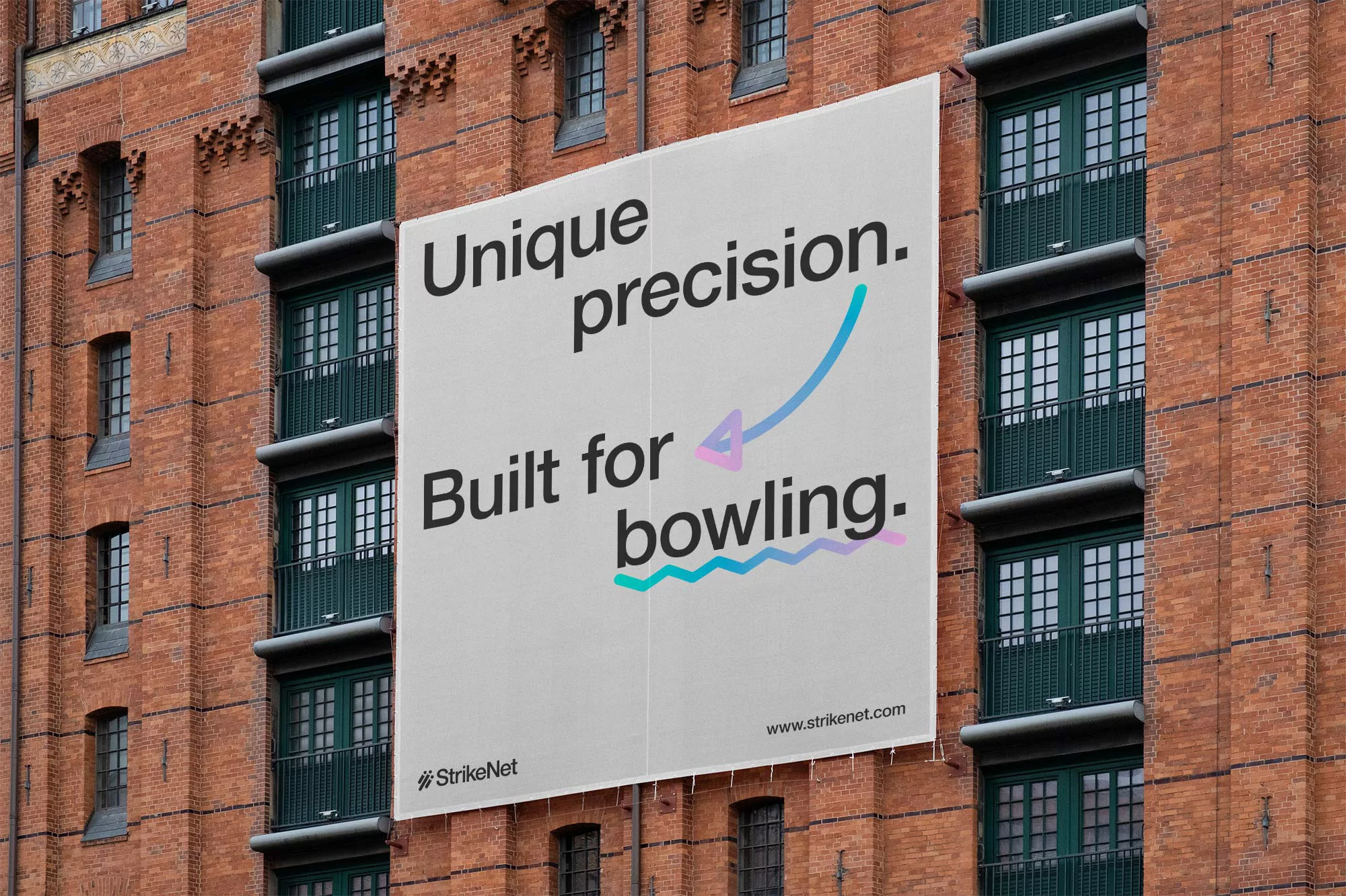 Outdoor billboard advertising StrikeNet bowling with unique precision messaging on brick building in natural daylight. Graphic elements visible.