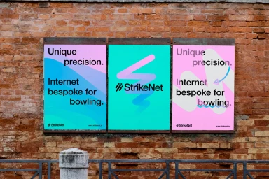 Three colorful typographic posters for StrikeNet mounted on an aged red brick wall above a metal railing.