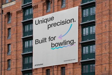 Large outdoor banner featuring StrikeNet typography mounted on a weathered red brick industrial building exterior.