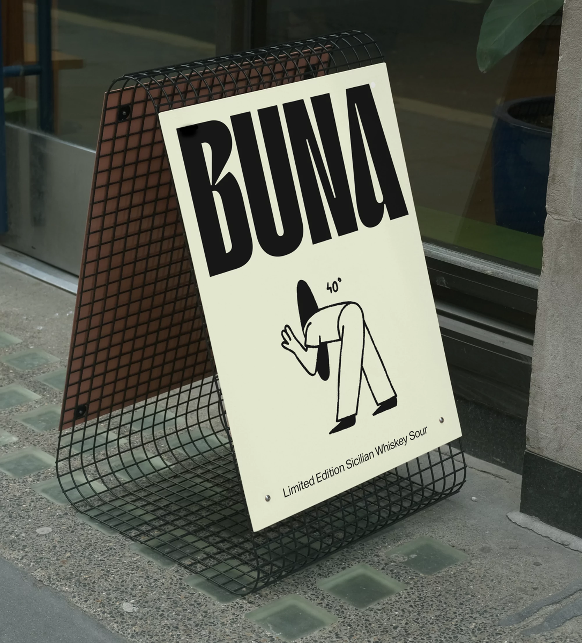 Sidewalk sign featuring the word 'BUNA' in bold black letters above an illustration of a figure bending over. The sign is metal.