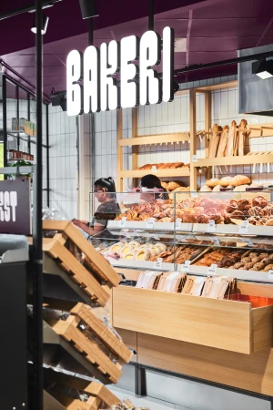 Bakery display with fresh baked goods, pastries, and breads, showcasing a variety of delicious options in a commercial setting.