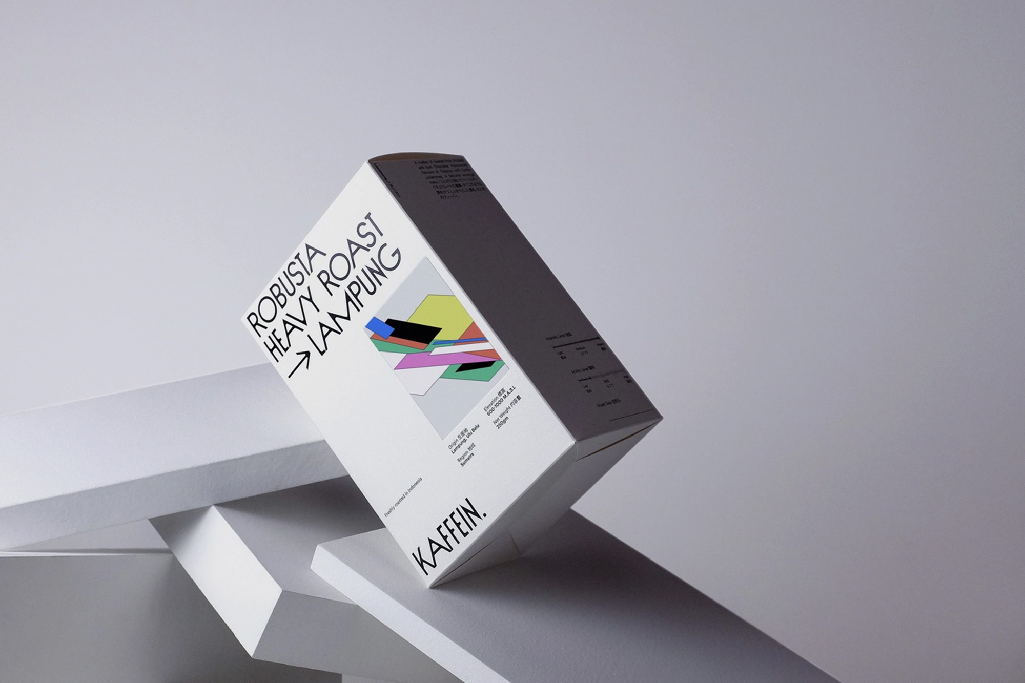 Studio product shot of a white box with black text and abstract geometric design elements balancing on geometric white blocks.