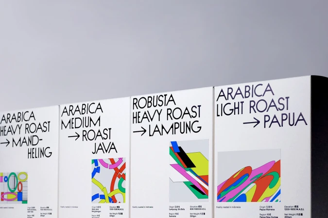 Four white coffee bags showcasing abstract designs and roast types like Arabica Heavy Roast and Robusta Heavy Roast, arranged closely together.
