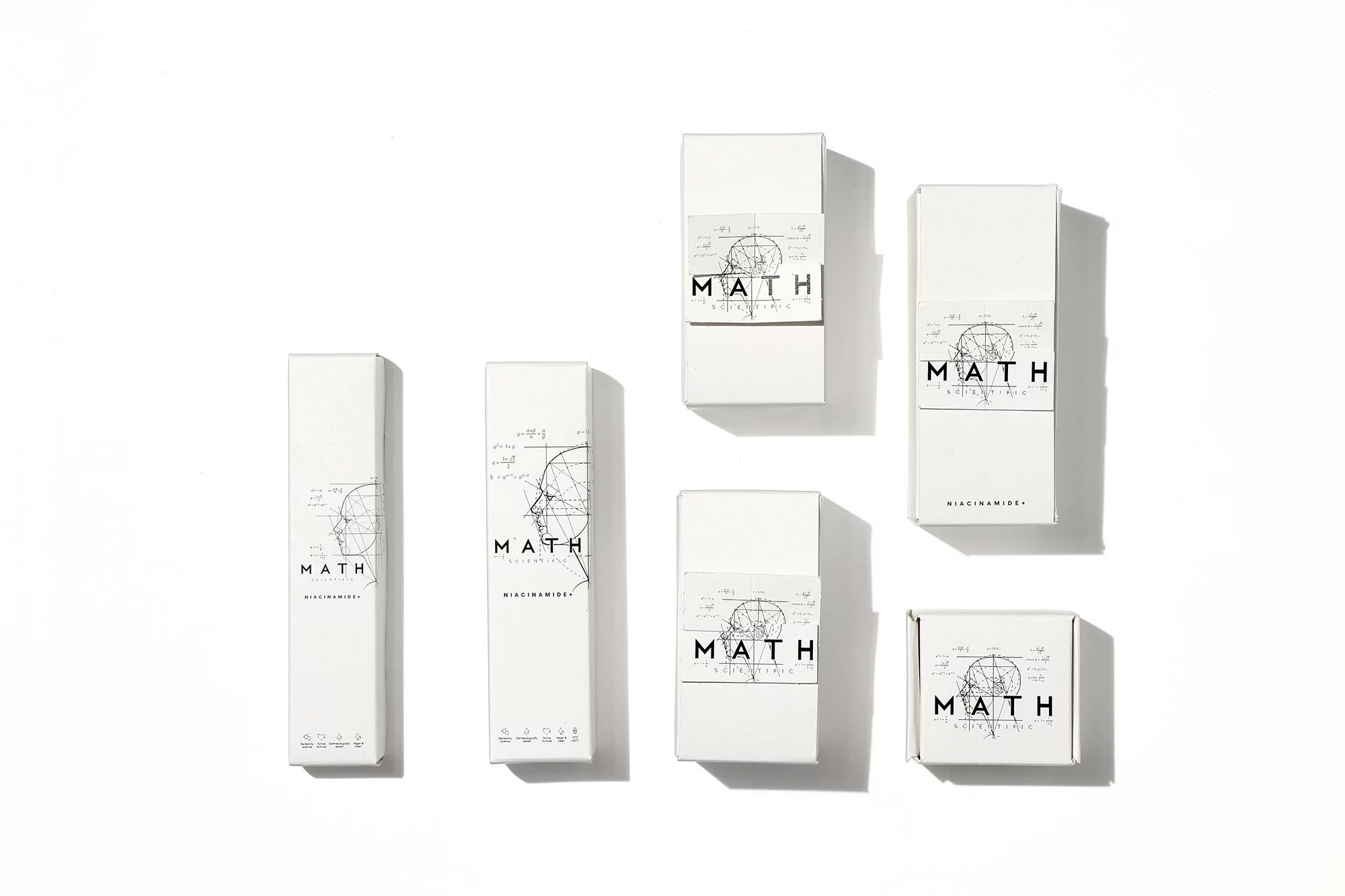Overhead shot of white boxes of various sizes with 'MATH' and geometric diagrams, on a bright white surface with soft shadows.