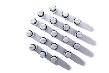 An overhead grid arrangement of white cosmetic bottles casting distinct diagonal shadows on a clean white background