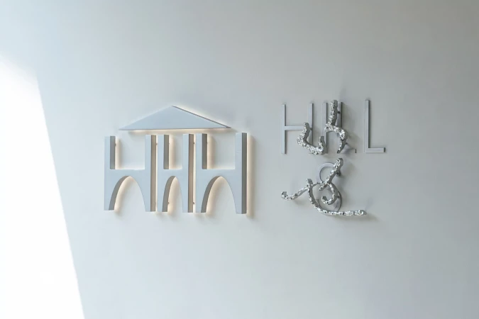 Minimalist white wall with an architectural logo featuring geometric shapes and artistic lettering for 'Hull & Hull'.