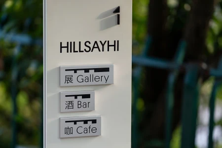 Vertical directional sign for HILLSAYHI featuring modern branding and wayfinding plaques for Gallery, Bar, and Cafe.