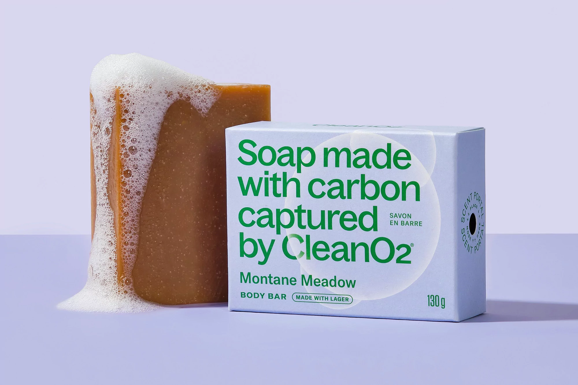 Still life shot of a bar of soap covered in foam beside product packaging with the words 'Soap made with carbon captured by CleanO2'.