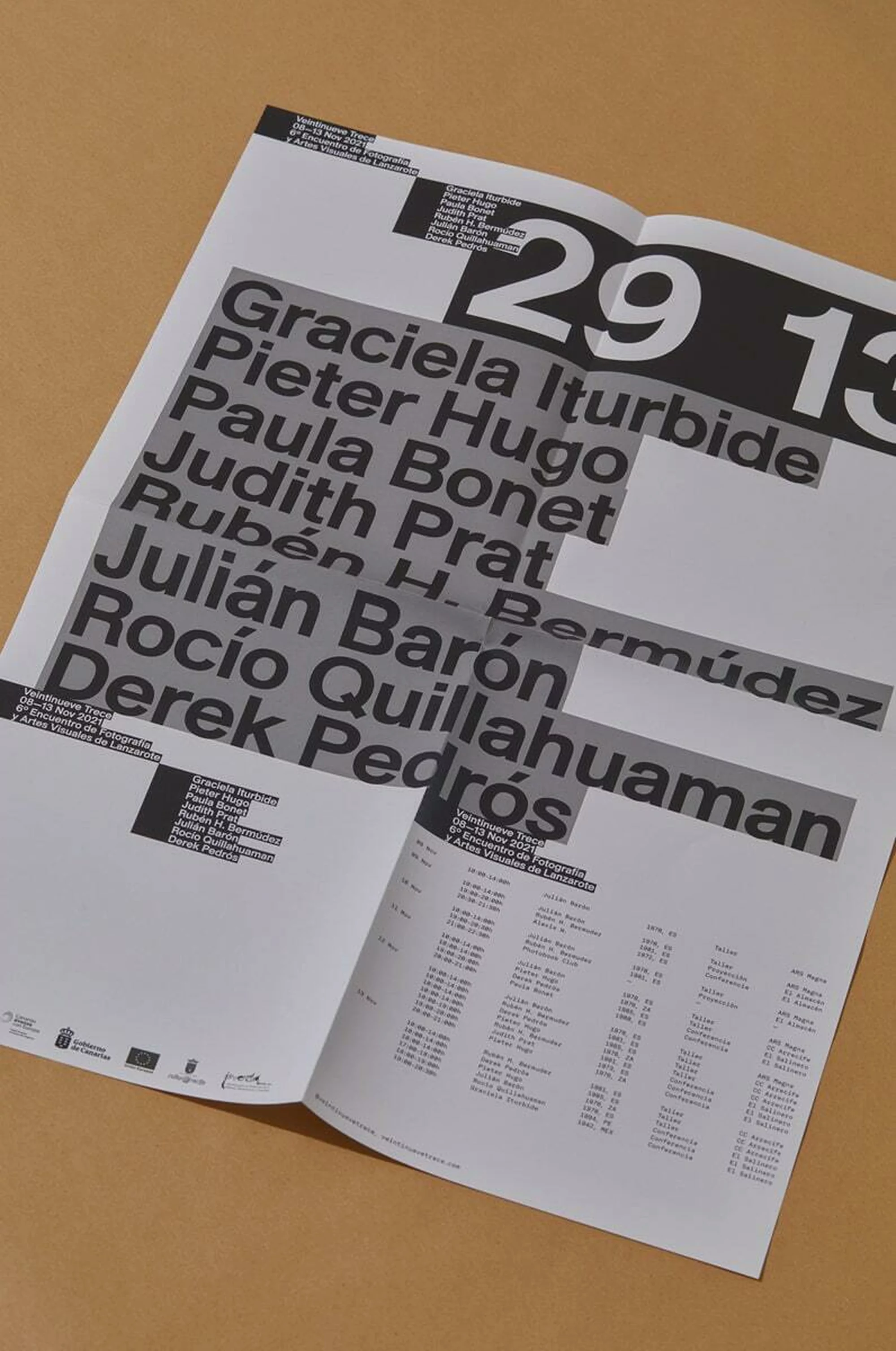 Open white poster on tan background features black text with a list of names and the numbers '29 13' in a clear, graphic design.