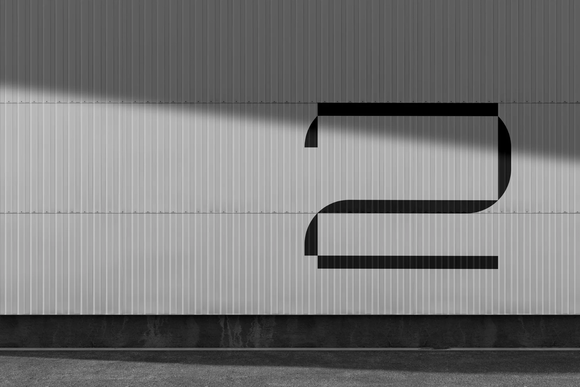 Abstract shot of a gray corrugated metal wall with a bold black number two graphic, minimalist aesthetic and strong geometric shapes.