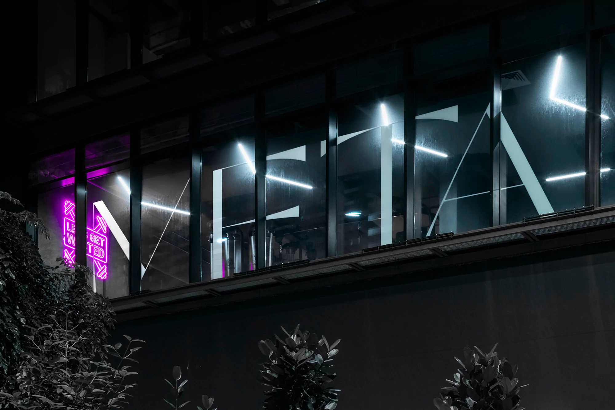 Illuminated 'META' signage on a modern building at night, featuring purple neon lights, creating a sleek, contemporary aesthetic.