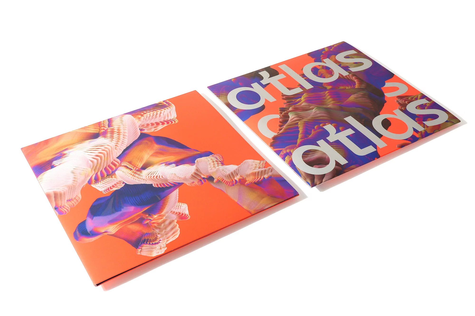 Two copies of 'Atlas' album art in orange tones with abstract layered imagery and sans-serif typography, displayed on a white surface.