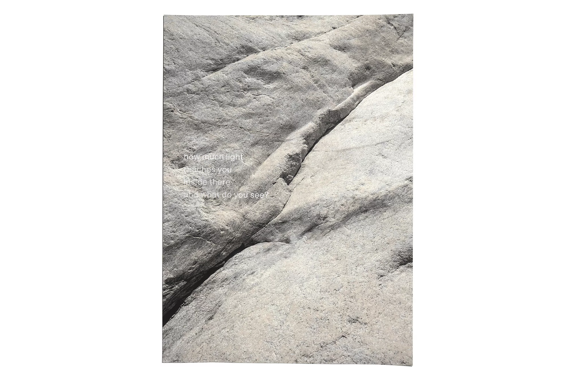 Close-up view of a grey rock face with a diagonal crevice and the phrase 'how much light reaches you inside there, and what do you see?'